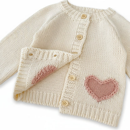 Front view of cream baby knit cardigan partially unbuttoned showing interior lining.