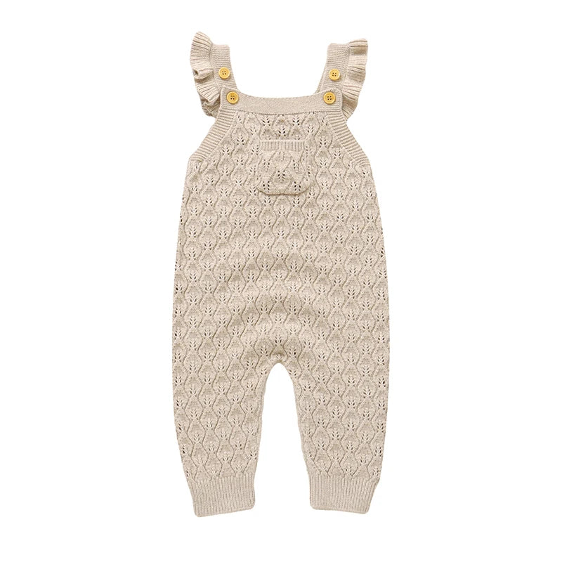 Baby girls beige neutral chunky knit sleeveless romper overalls with ruffle straps and a front pocket, laying flat on a white background.