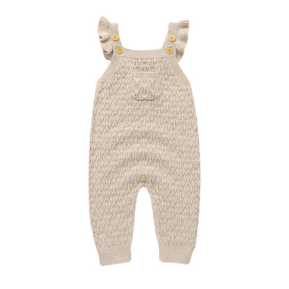 Baby girls beige neutral chunky knit sleeveless romper overalls with ruffle straps and a front pocket, laying flat on a white background.