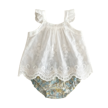 Two-piece baby girls summer outfit in Wildflower Meadow featuring a white eyelet embroidered ruffled camisole top and matching vintage-style floral bloomer shorts, flat lay on white background.