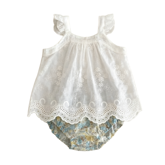 Two-piece baby girls summer outfit in Wildflower Meadow featuring a white eyelet embroidered ruffled camisole top and matching vintage-style floral bloomer shorts, flat lay on white background.