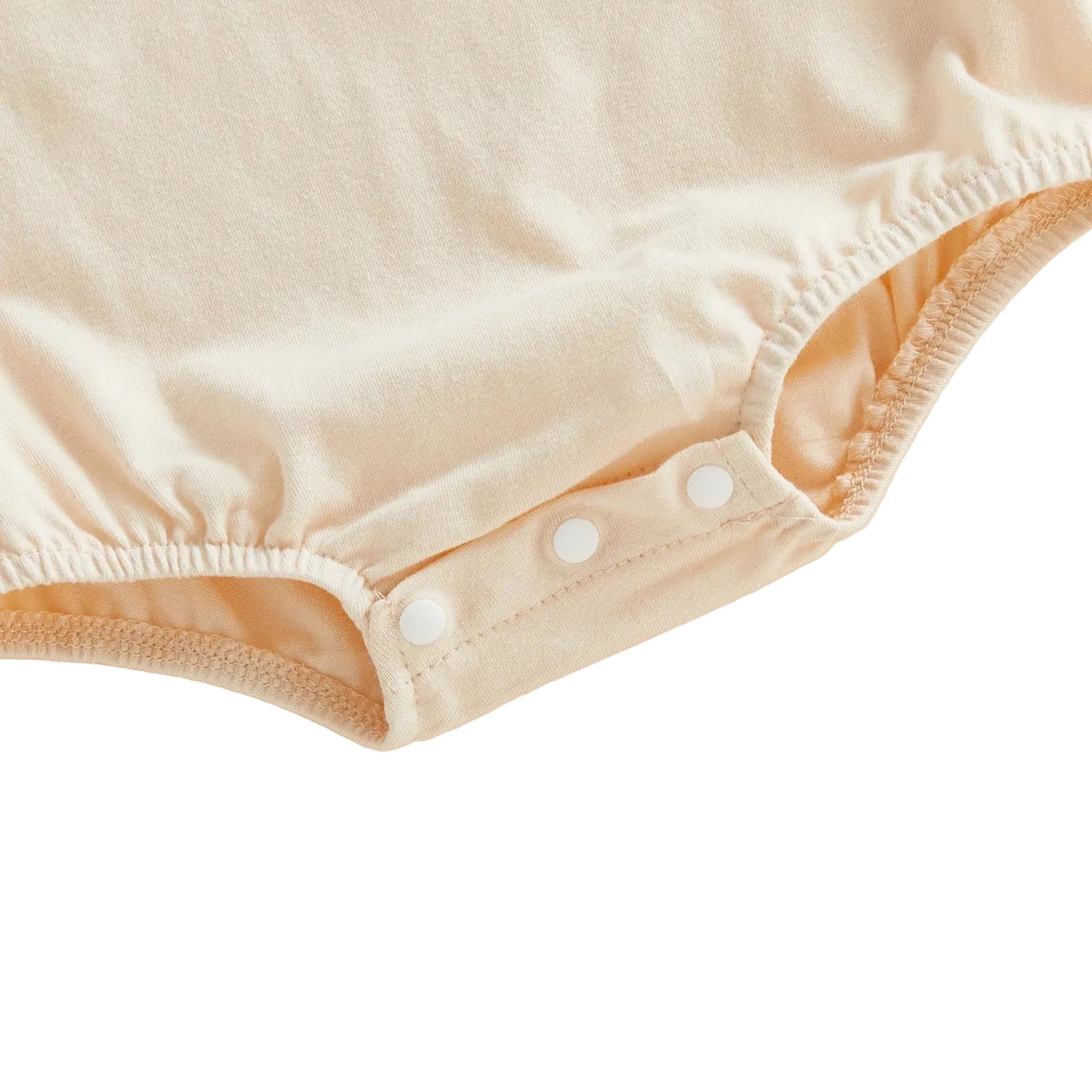 Close-up showing the three bottom snap closures for easy diaper changes on the cream baby bodysuit.