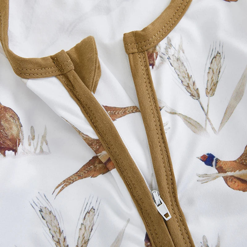 Close-up of the smooth front zipper slightly unzipped on the white baby romper with upland hunting pheasant print.