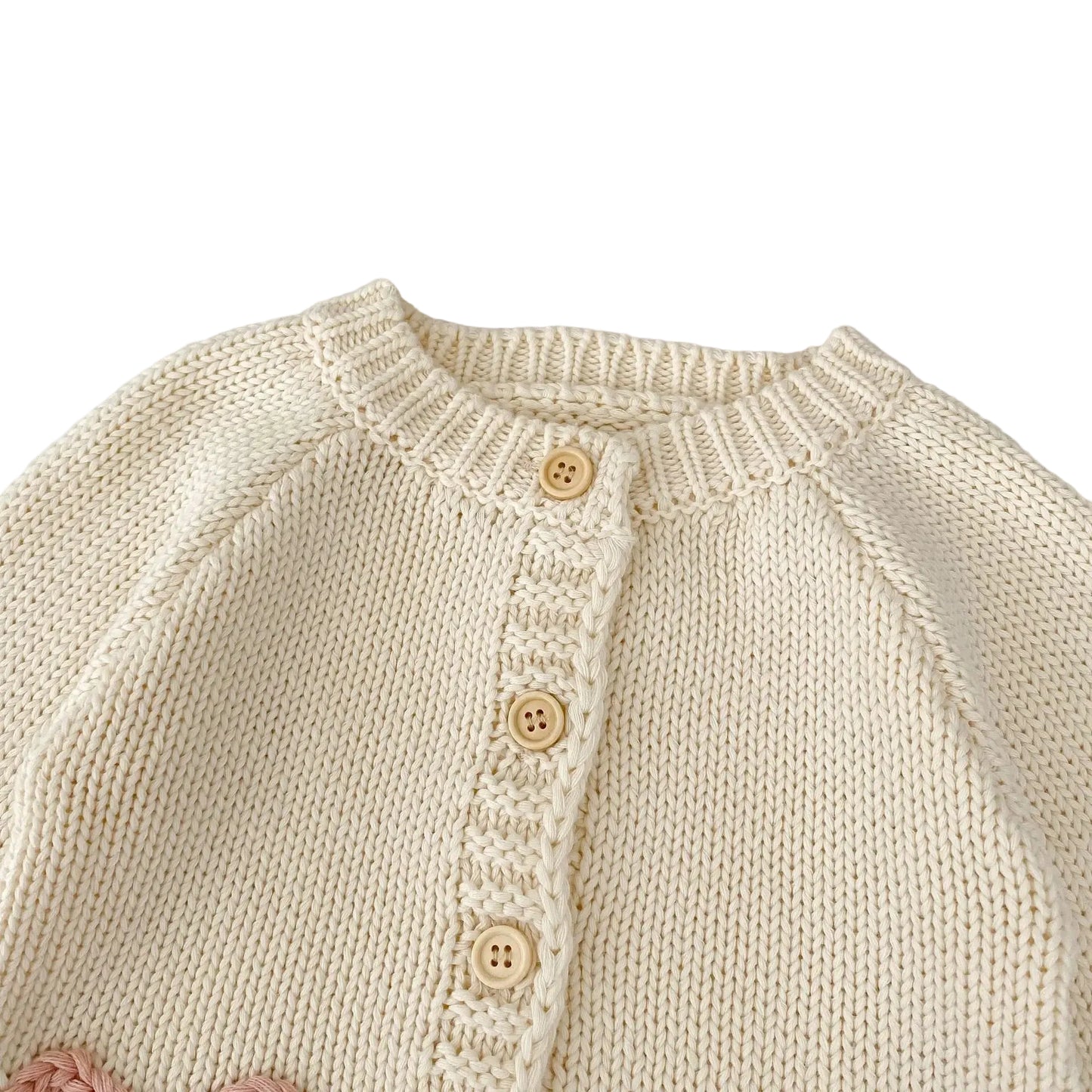 Close-up of ribbed crew neckline and top buttons on cream baby girls cardigan.