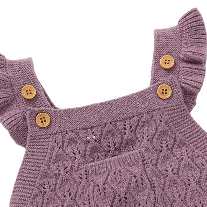 Close-up of the sweet ruffle shoulder straps and classic wooden-style buttons on a soft mauve baby knit jumpsuit.