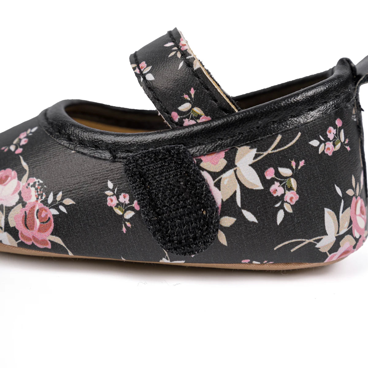 Side view of a black floral crib shoe highlighting the secure velcro Mary Jane strap.