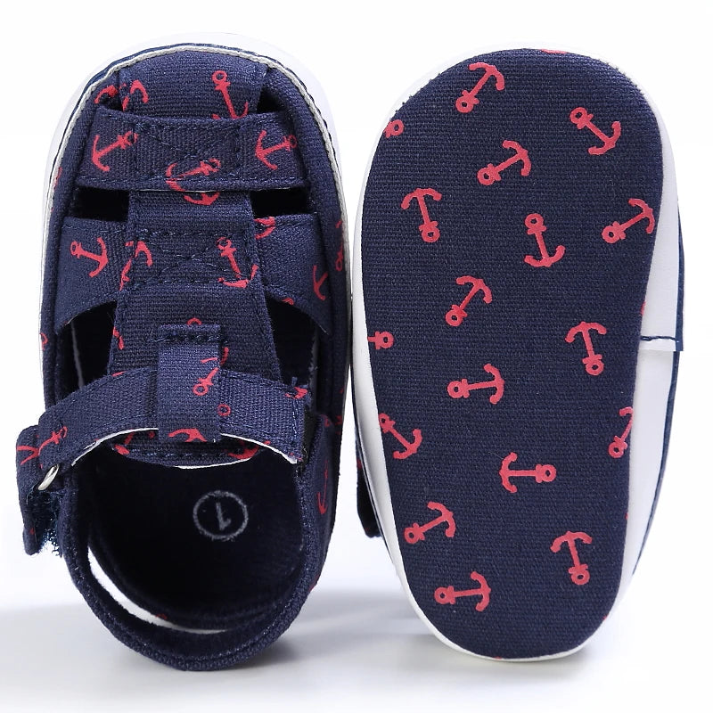 Top down and bottom sole view of a navy blue baby canvas boat shoe showing the red anchor anti-slip grip pattern.