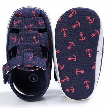 Top down and bottom sole view of a navy blue baby canvas boat shoe showing the red anchor anti-slip grip pattern.