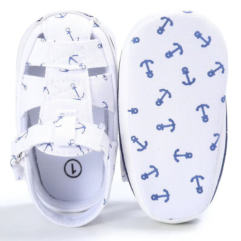 Top down and bottom sole view of a white baby canvas boat shoe showing the blue anchor anti-slip grip pattern.