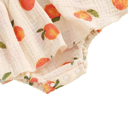 Close-up showing the bottom snap closures for easy diaper changes on the baby girl peach print romper dress.