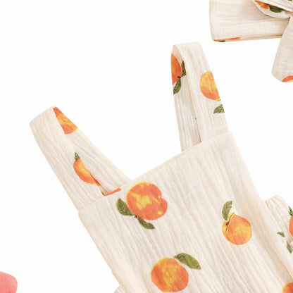 Close-up detail of the square neckline and breathable cotton gauze fabric texture of the baby peach print romper.