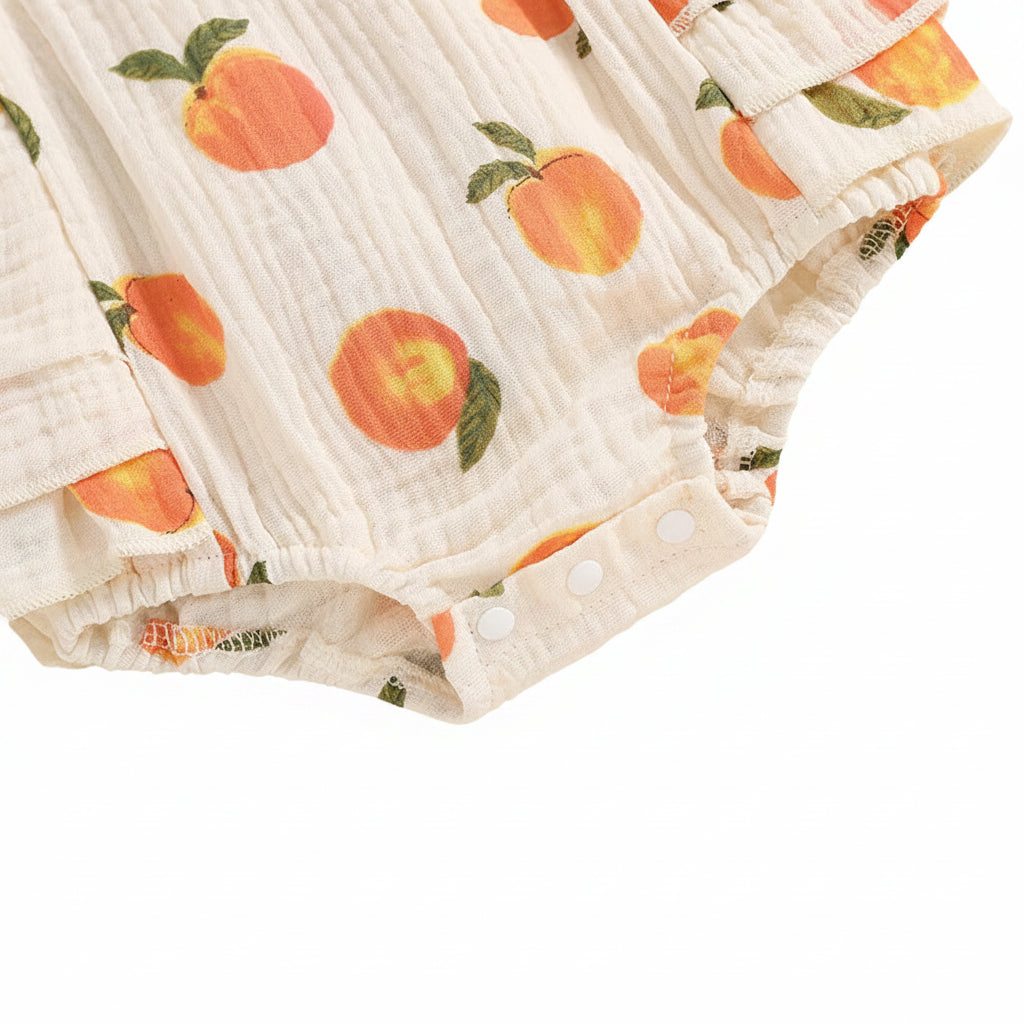 Detail view of the bottom snap closures on the baby peach print jumpsuit for easy diaper changes.