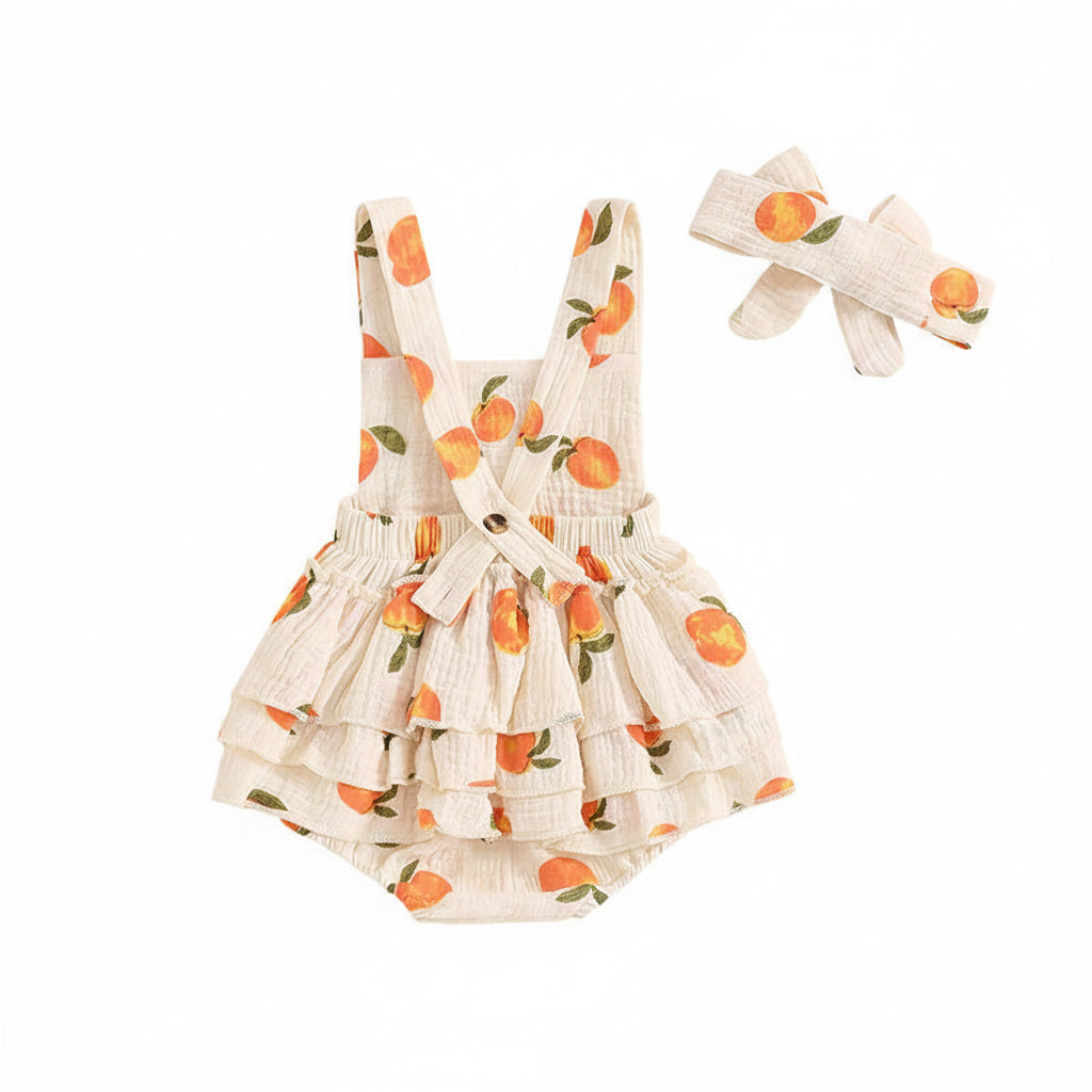 Flat lay back view of the baby girls peach print romper showing criss-cross straps and tiered ruffles.