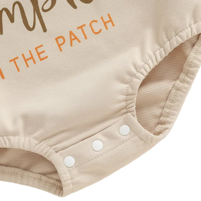 Close-up of the three bottom snap closures on the beige baby romper designed for easy diaper changes.