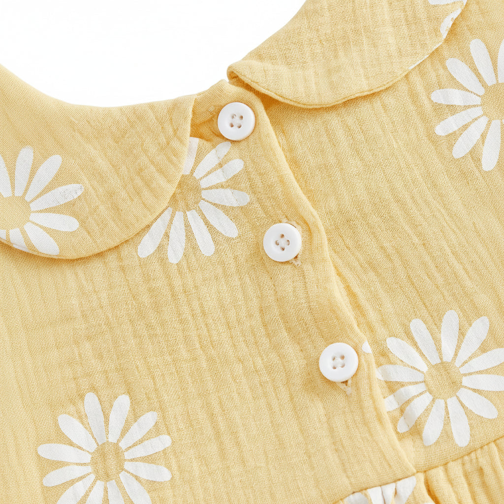 Close-up of the functional white button closures on the back of the yellow daisy print baby girl romper dress.