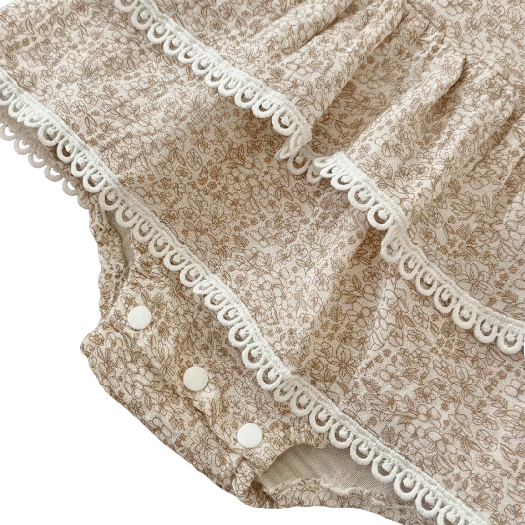 Close-up of the durable bottom snap closures for easy diaper changes and the tiered ruffle lace hem on the floral baby bodysuit.