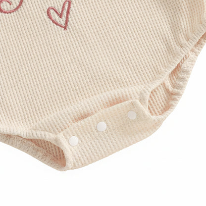 Close up of the convenient bottom snap closures on the baby girl waffle knit bodysuit.