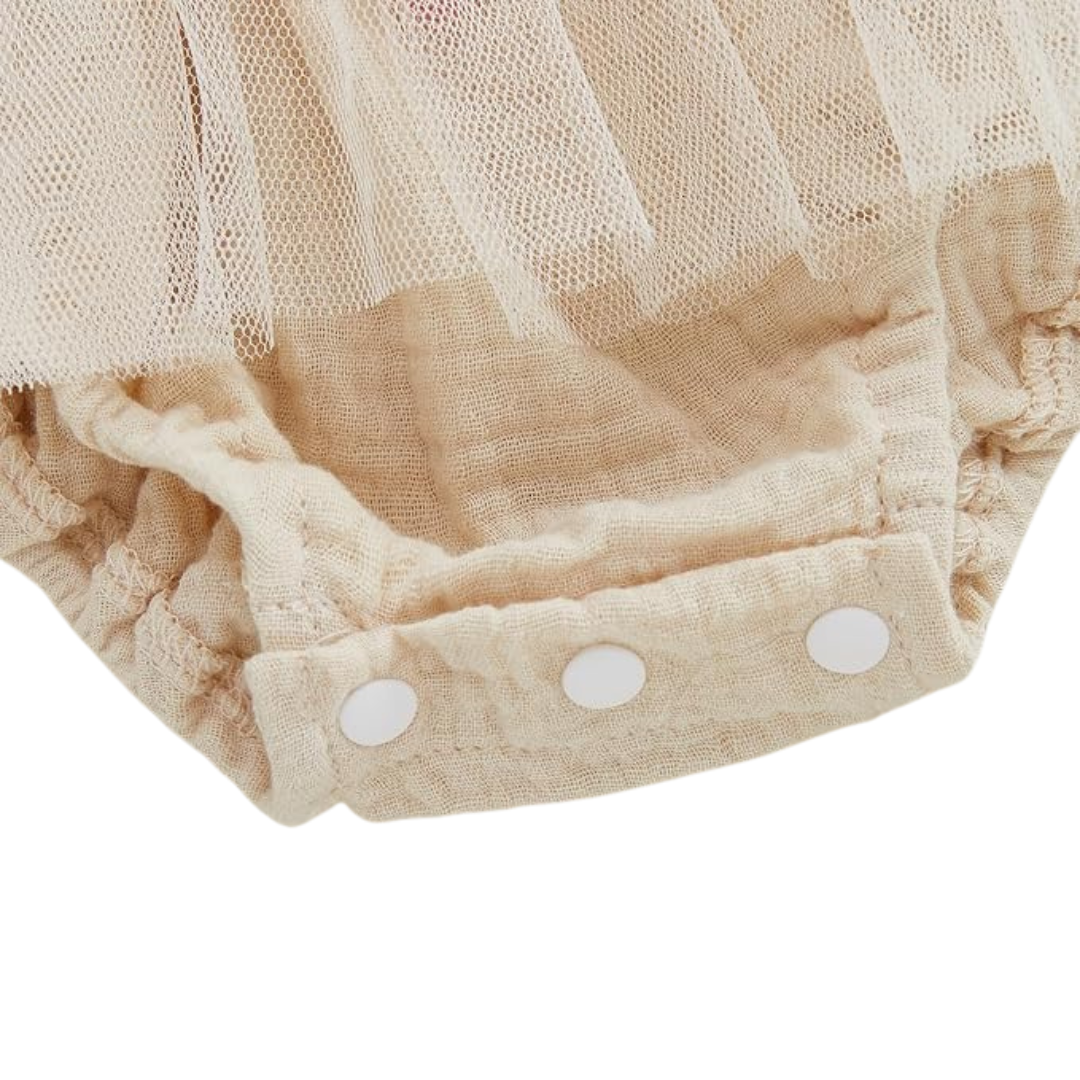 Close up view of snap button closures on cream baby girl romper jumpsuit for easy diaper changes