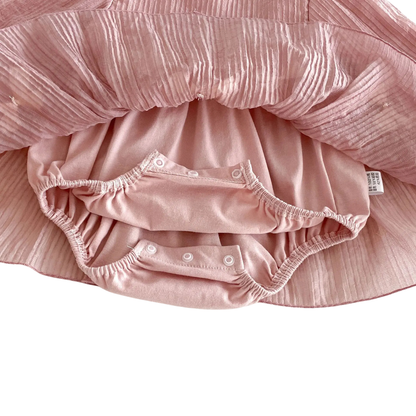 Underneath view of the baby girl romper dress revealing the hidden soft cotton bodysuit with snap closures for easy diaper changes.