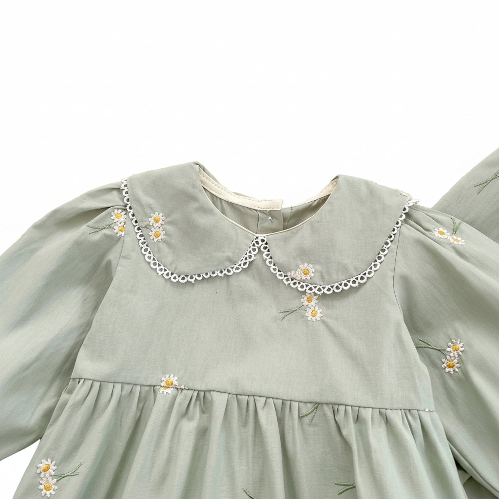 Close-up detail of the classic Peter Pan collar with delicate white scalloped lace trim and floral embroidery on a sage green baby romper.