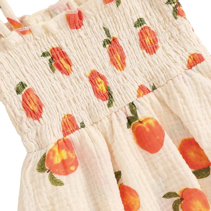 Close-up detail showing the stretchy smocked bodice and cute peach and leaf pattern on the baby girl romper dress.