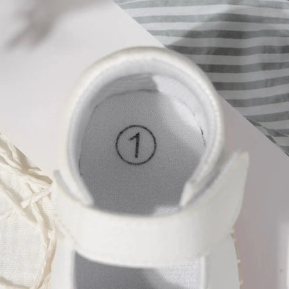 Top-down view into the interior of a white baby shoe, clearly displaying a size 1 printed on the insole.