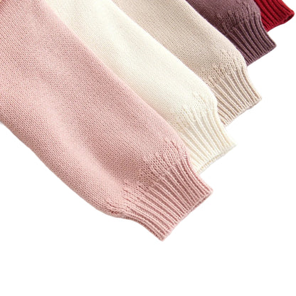 Close-up of stretchy ribbed wrist cuffs on stacked long sleeve baby knit rompers.