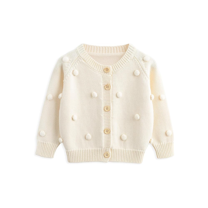 Front view of the baby and toddler girls cream cotton knit cardigan featuring 3D pom-poms and wooden buttons.