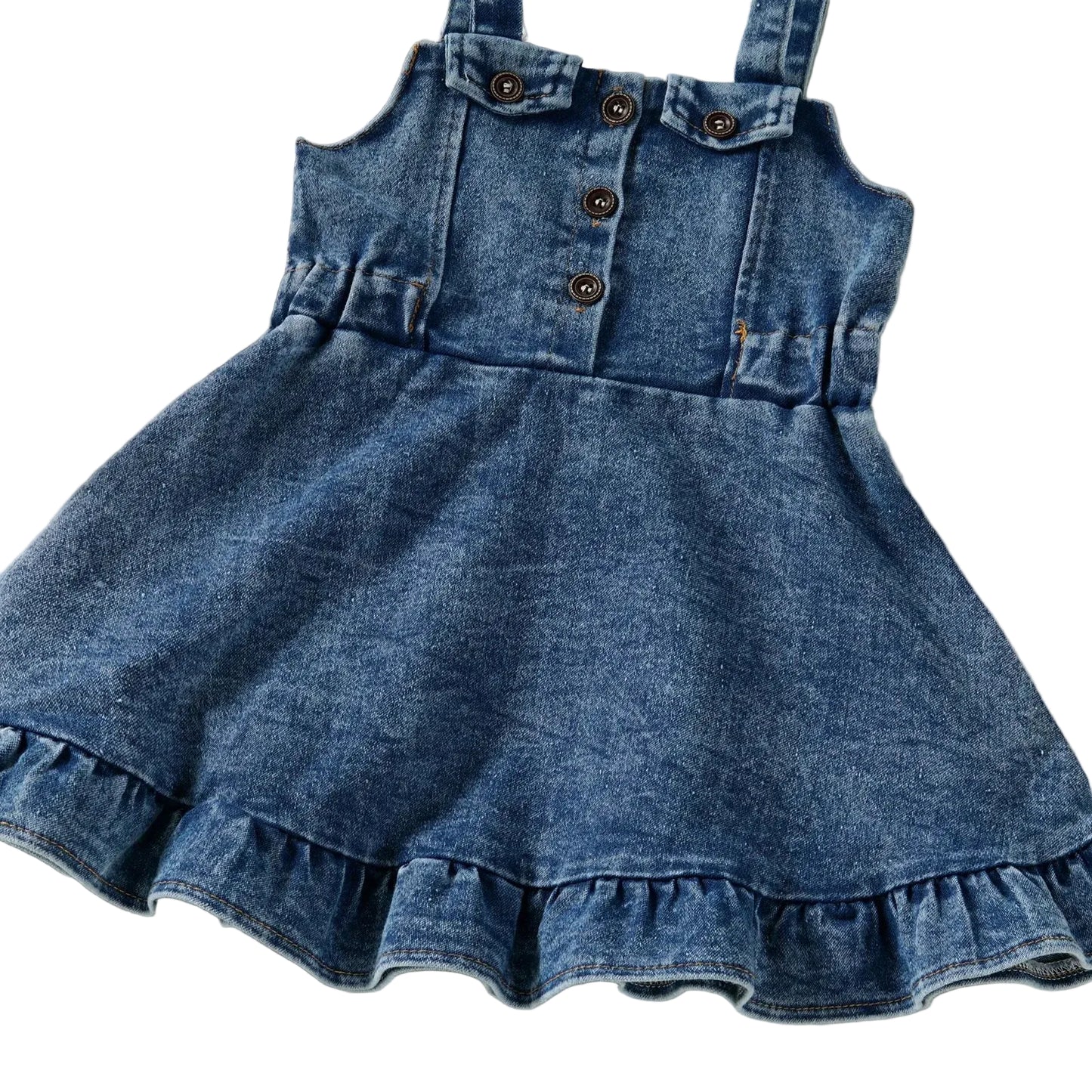 A full front view of the baby and toddler girls blue denim overall dress highlighting the flared A-line silhouette and ruffle bottom.