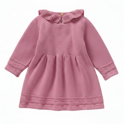 Back view of a pink long sleeve cable knit sweater dress for toddlers showing the neck button and waist pleats.