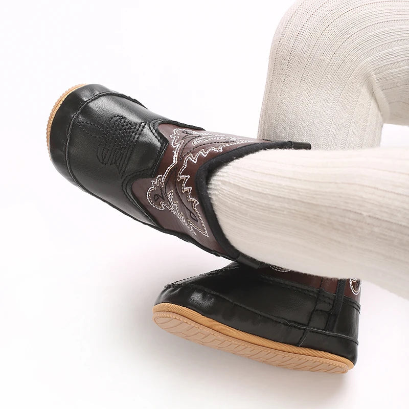 Baby wearing black and brown waterproof western boots for winter.