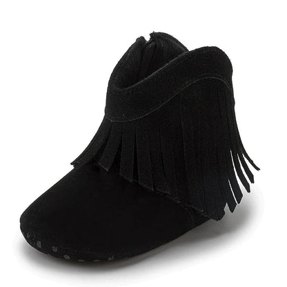 Studio side profile view of a black baby western fringe moccasin bootie on a white background.