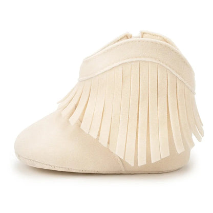 Studio side profile view of a cream infant fringe suede moccasin bootie on a white background.