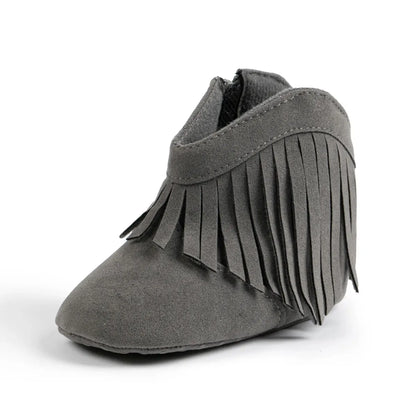 Studio side profile view of a gray baby western fringe moccasin bootie on a white background.