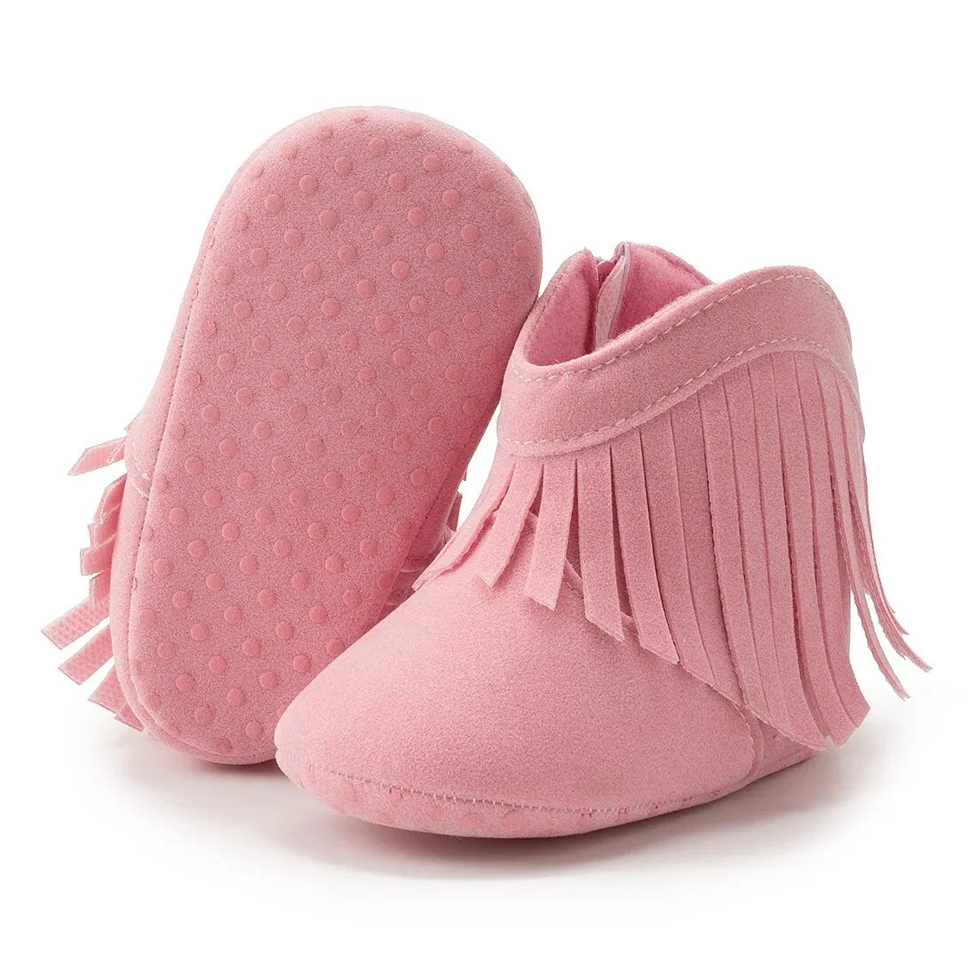 Pink infant fringe suede moccasin booties showing the soft, textured anti-slip dotted sole on a white background.