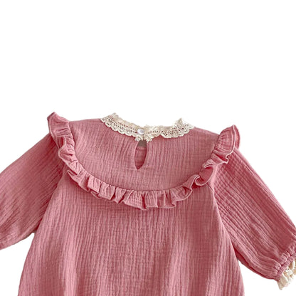 Back view of the neckline on a pink baby jumpsuit featuring a ruffle collar detail, small keyhole opening, and a single white button closure.