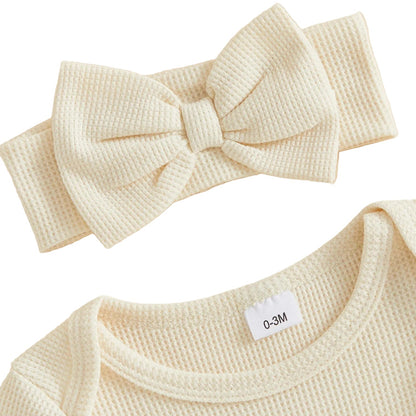 Back view of the cream "My first Halloween" baby romper showcasing the tiered ruffle butt detail and matching bow headband.