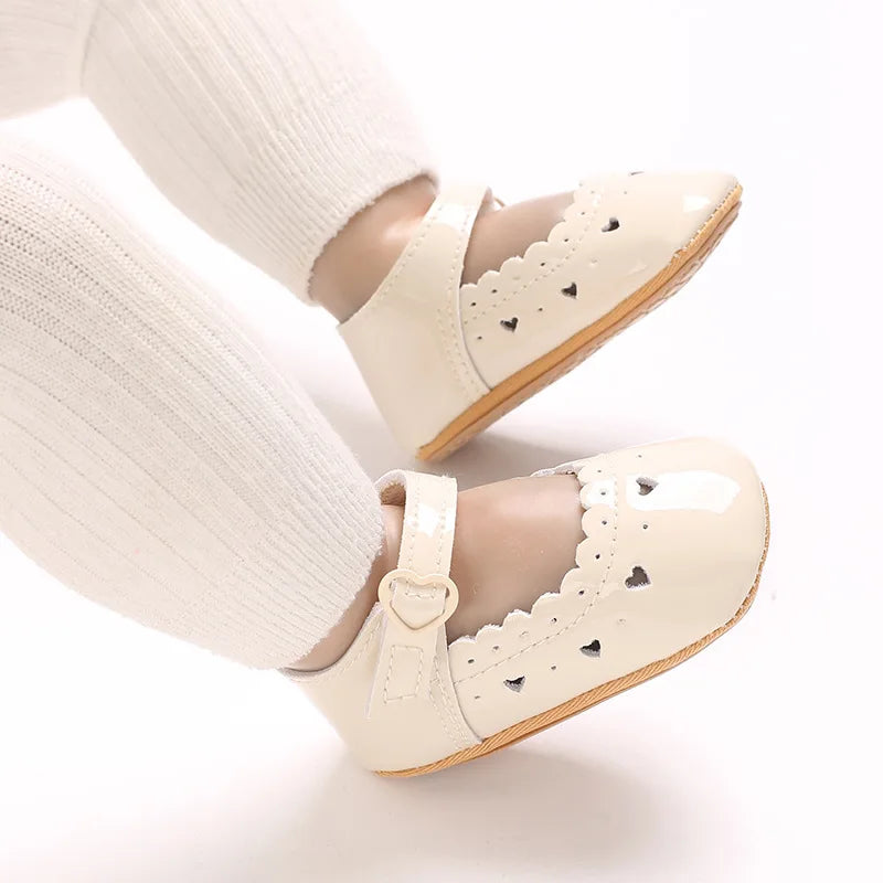 Baby wearing beige soft-sole Mary Jane dress shoes with white tights.