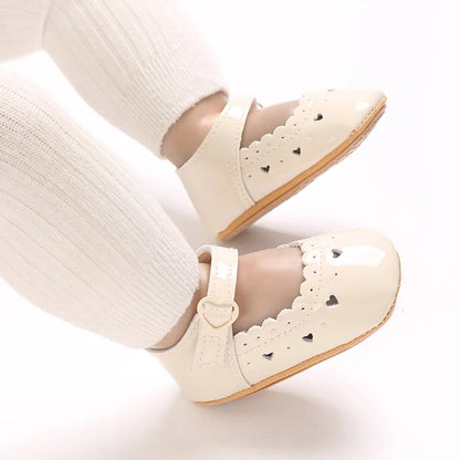 Baby wearing beige soft-sole Mary Jane dress shoes with white tights.
