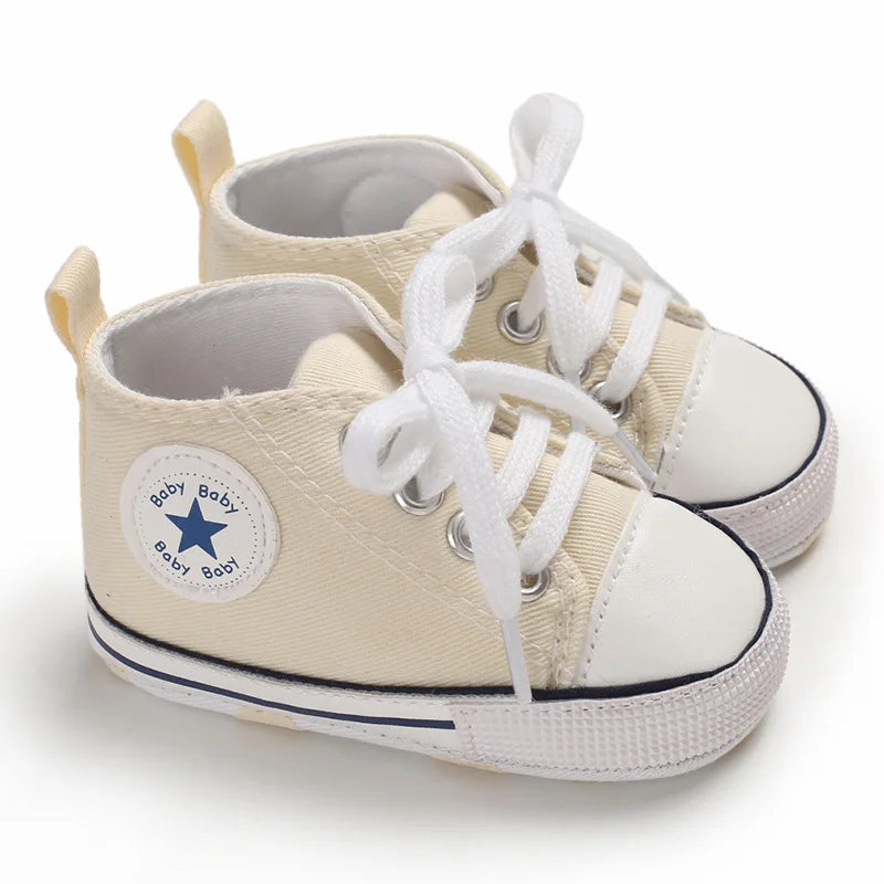 Cream beige canvas baby sneakers with soft flexible soles for unisex infants.