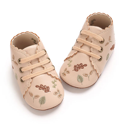 Top-down view of beige scalloped baby girl crib shoes.