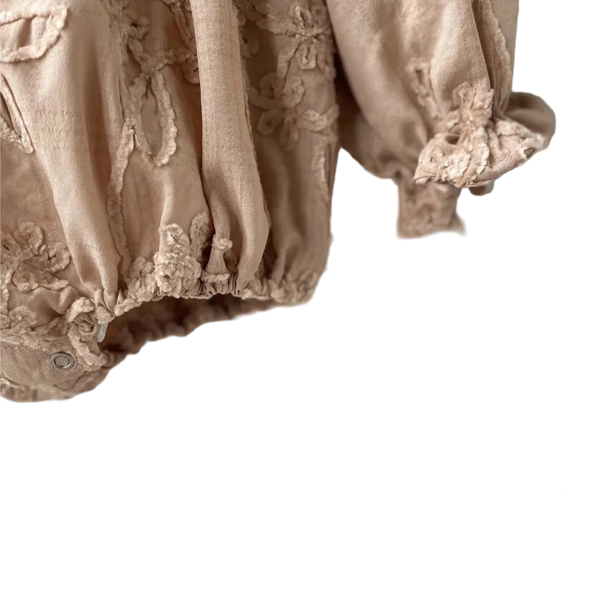 Close-up view of the gathered elastic ruffle cuff and detailed floral embroidery on the beige long sleeve romper.