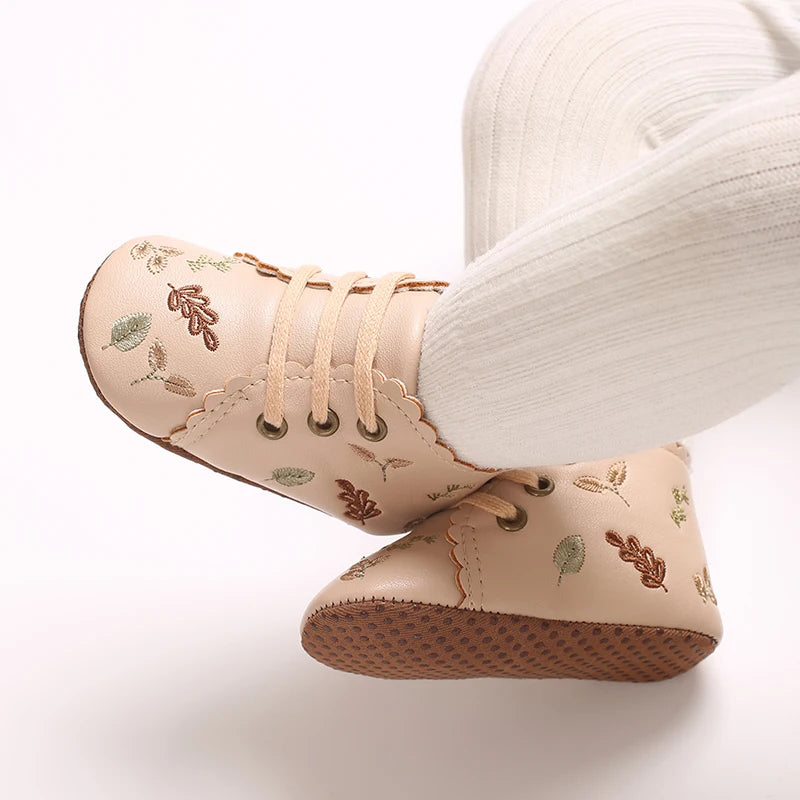 Baby wearing beige embroidered soft sole pre-walker booties.