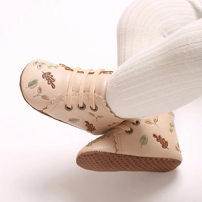 Baby wearing beige embroidered soft sole pre-walker booties.