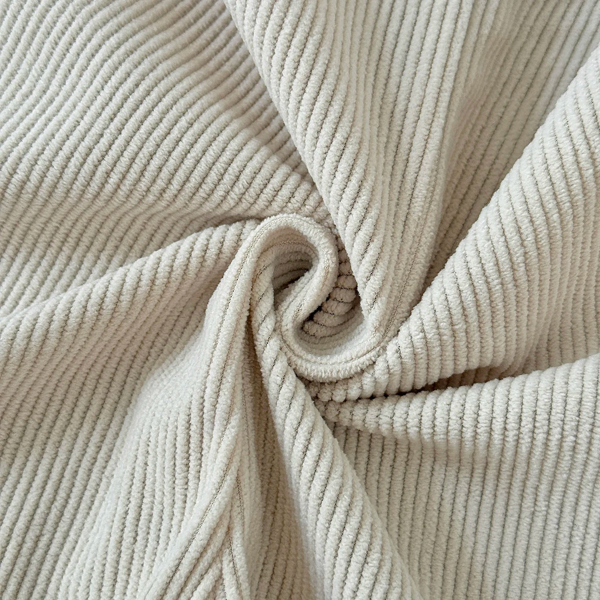 Macro close-up showing the soft, ribbed corduroy fabric texture of the Kidsely baby overalls in a neutral beige color.