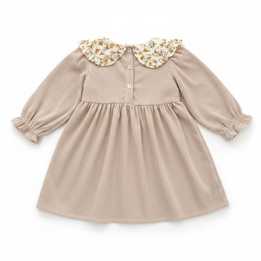 Back view of the beige ribbed corduroy toddler dress showing the button closures at the neckline.