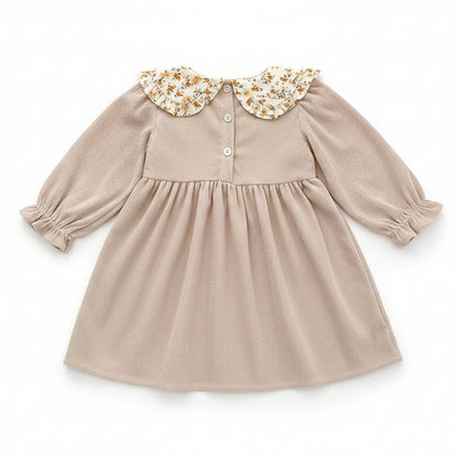 Back view of the beige ribbed corduroy toddler dress showing the button closures at the neckline.