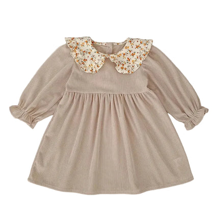 Front view of a beige ribbed corduroy long-sleeve toddler dress with a floral ruffled Peter Pan collar.