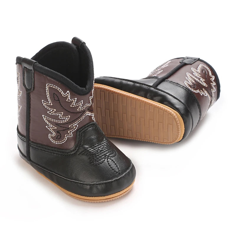 Pair of black and brown toddler cowboy boots with white stitching, showing the textured rubber sole.