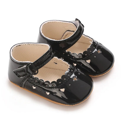 Black patent vegan leather Mary Jane shoes for baby girls with heart cutouts.